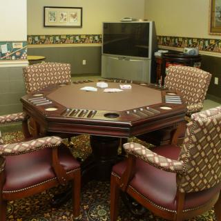 A cozy game room featuring a poker table surrounded by comfortable leather chairs, ready for a card game.