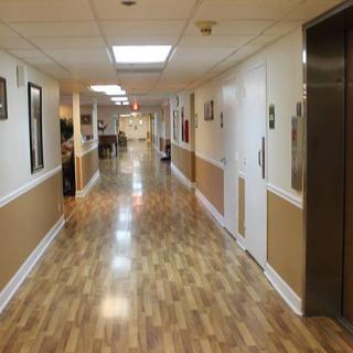 A long hallway with wooden flooring and an elevator on the right side.
