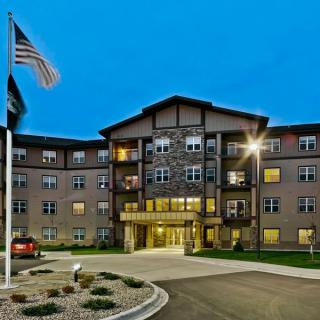 A well-lit residential building at night with an American flag in the foreground.