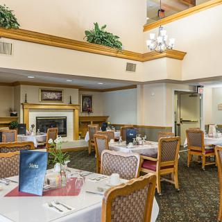A spacious dining area with neatly arranged tables and a cozy fireplace.
