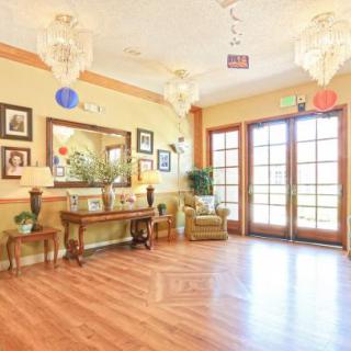 A warmly decorated lobby with chandeliers, wooden flooring, and elegant furniture.