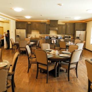 A well-furnished dining area with tables and chairs, adjacent to a kitchen space.