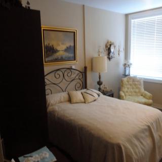A cozy bedroom with a neatly made bed, decorative pillows, and elegant furnishings.