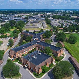 Aerial view of a residential and commercial area with roads and green spaces.