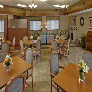 A well-lit dining area with multiple tables and chairs, decorated with flowers.