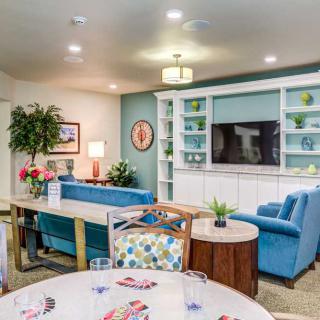 A cozy and modern living room with blue sofas, built-in shelves, and a television.