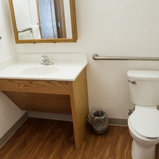 A clean and simple bathroom with a sink, toilet, and mirror.