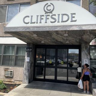 A person standing near the entrance of the Cliffside apartment building.