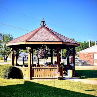 A lovely wooden gazebo nestled in a green lawn under a clear blue sky.