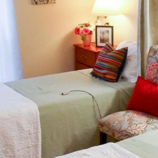 A cozy bedroom with twin beds, colorful pillows, and a warmly lit nightstand.
