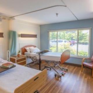 A well-lit hospital room with two beds, a large window, and modern furnishings.