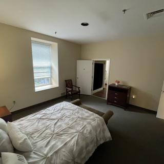 A tidy bedroom featuring a bed, chair, window, and dresser.