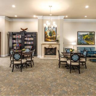 A cozy living room with a fireplace, bookshelves, and arranged seating.