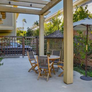 A cozy outdoor patio setup with a table, chairs, and an umbrella under a pergola.