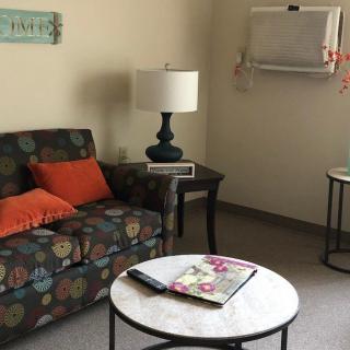 A cozy living room with a patterned sofa and vibrant cushions, accompanied by a lamp and tables.