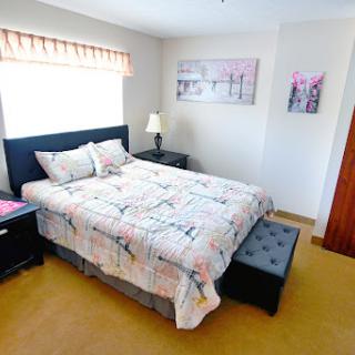A cozy and well-decorated bedroom featuring a neatly made bed, elegant nightstands, and decorative artwork.