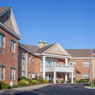 A two-story brick building with a grand entrance on a clear day.