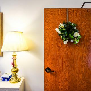 A cozy interior featuring a lit lamp and a wooden door adorned with a floral wreath.