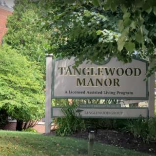 Sign for Tanglewood Manor surrounded by lush greenery.