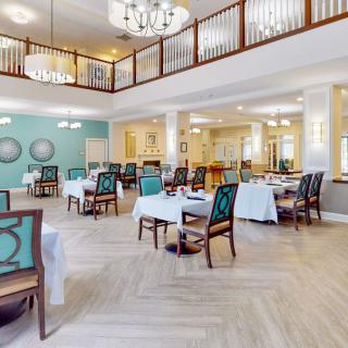 A spacious and elegantly designed dining area with tables, upholstered chairs, and chandeliers.