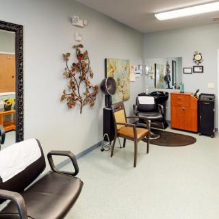 A cozy hair salon interior featuring chairs, a mirror, and styling equipment.