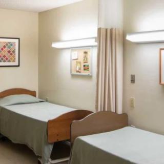 A clean and organized hospital room with two beds and wall decor.
