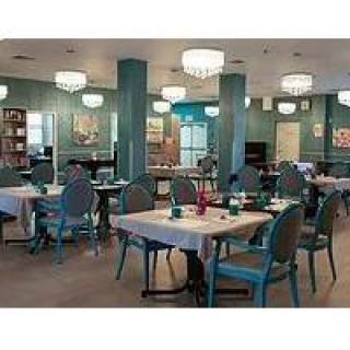 A well-decorated dining area with elegantly set tables and stylish chairs, illuminated by chandeliers.