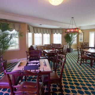 A neatly arranged dining room with elegant tables and chairs, adorned with a chandelier and patterned carpet.