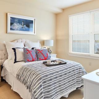 A cozy and modern bedroom with a neatly made bed, decorative pillows, and a window letting in natural light.