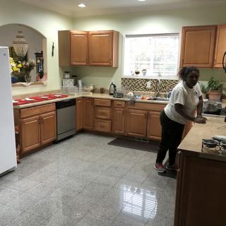 A person standing in a spacious, well-equipped kitchen with wooden cabinets and modern appliances.