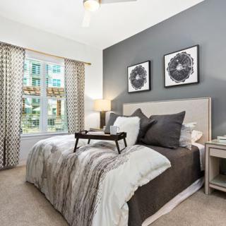 A modern and cozy bedroom with neutral tones, featuring a large bed, stylish decor, and a well-lit window.