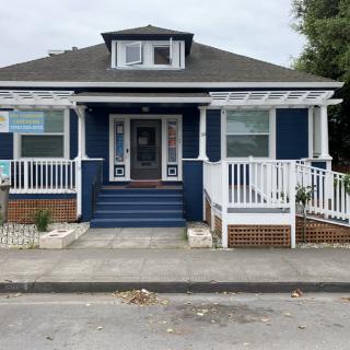 A charming blue bungalow with a welcoming front porch and steps.