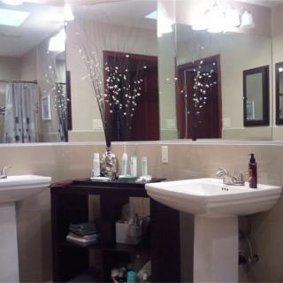 A neatly arranged bathroom with two pedestal sinks, large mirrors, and decorative elements.