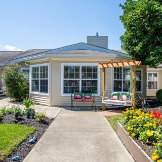 A charming house with a well-maintained garden and outdoor seating area on a sunny day.