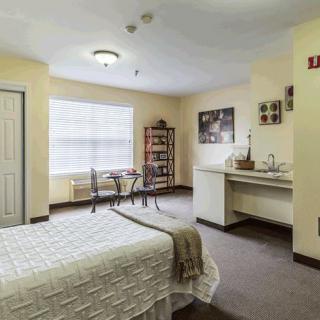 A cozy bedroom with a bed, a small dining area, and ample natural light.