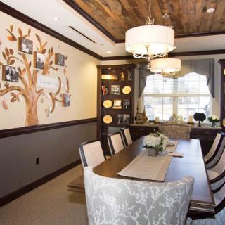 A beautifully designed dining room featuring a wooden ceiling, elegant chandeliers, and a wall adorned with family photo tree art.