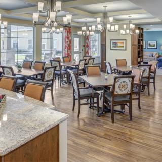 A spacious dining area with multiple tables, chairs, and elegant chandeliers.