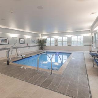 A modern indoor swimming pool with surrounding seating and ample lighting.