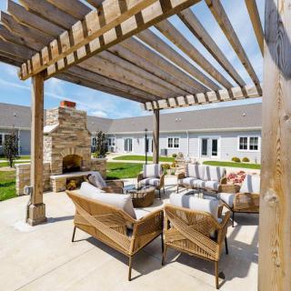 A beautifully furnished patio featuring a wooden pergola and outdoor fireplace.