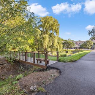 A scenic pathway with a wooden bridge surrounded by lush greenery in a serene park setting.