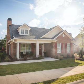 A picturesque suburban brick house with a well-maintained lawn.