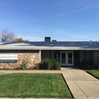 A well-maintained residential building with a grassy front yard and clear blue sky.