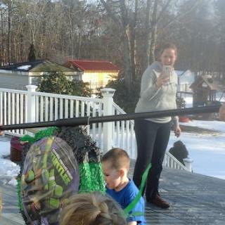A joyful moment outdoors in the winter, where children are playing in the snow while an adult watches over.
