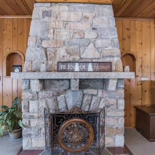 A rustic stone fireplace in a wood-paneled room with decorative accents.
