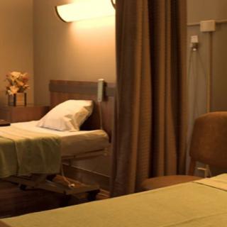 A dimly lit hospital room with a medical bed and privacy curtains.