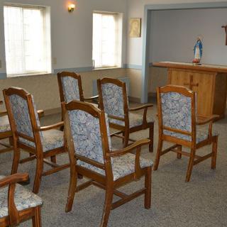 A small chapel with wooden chairs facing an altar.