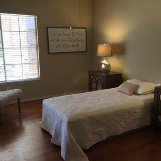 A minimalist bedroom with a single bed and a side table lamp.