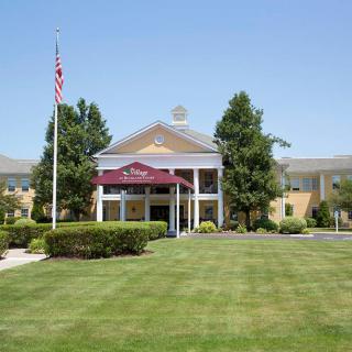 The entrance of a hotel with a landscaped lawn and flagpole.