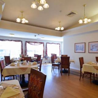 An elegant dining room with neatly arranged tables and chairs, illuminated by warm chandelier lighting.