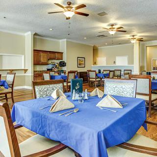A neatly arranged dining area with blue tablecloths and elegant place settings.